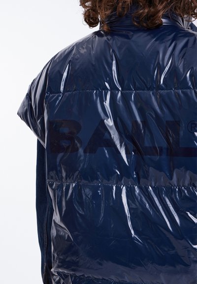 Tamsiai mėlynas pūkinis liemenė, pagaminta iš blizgaus medžiagos, su aukštu apykaklės dizainu ir dideliu "BALL" logotipu, atspausdintu per nugarą.