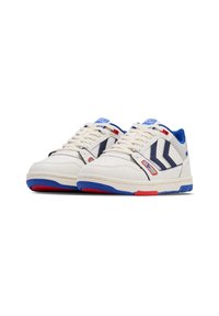 Baskets blanches avec des accents bleus et rouges ; tige en cuir lisse, avant perforé, et semelle en caoutchouc avec un motif de crampons.