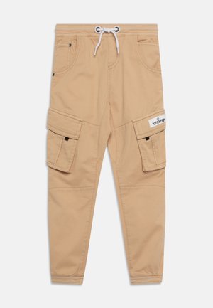 Pantalon cargo beige avec taille élastique et cordon blanc, poches avant, poches latérales à rabat et étiquette de marque sur le rabat de la poche droite.