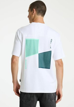 Homme de dos portant un t-shirt blanc avec deux motifs carrés géométriques turquoise et le texte vertical "CHASIN'" au dos.