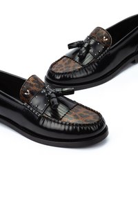 Mocassins en cuir verni noir avec un devant en imprimé léopard, des glands décoratifs et des clous sur le dessus, avec un bout rond et une semelle plate.