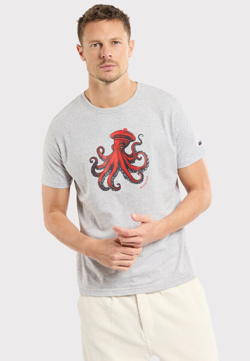 T-shirt gris à manches courtes avec un grand graphique de pieuvre rouge et des accents noirs. Le tissu semble doux, avec un col rond et une coupe décontractée.