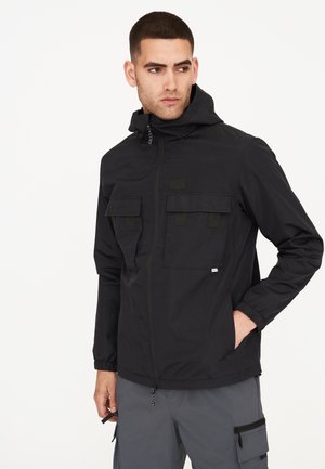 Schwarze leichte Jacke mit Kapuze, zwei großen Fronttaschen, elastischen Bündchen und Reißverschluss, aus wasserabweisendem Material gefertigt.