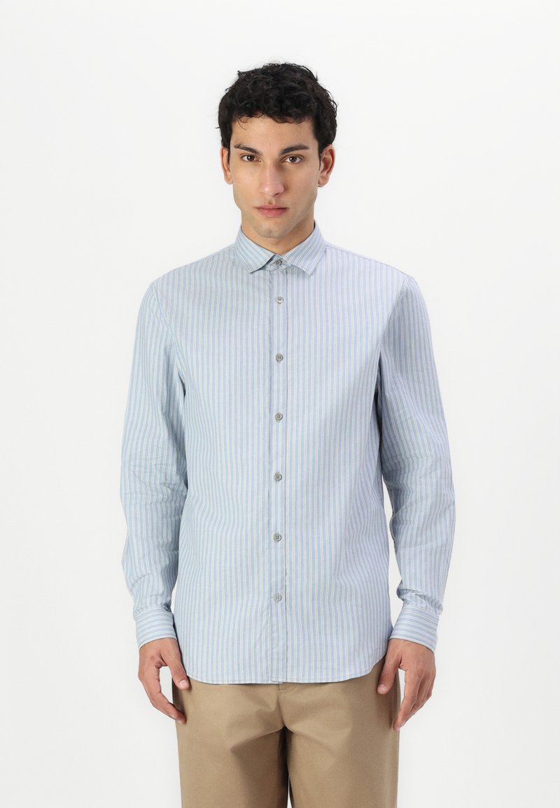 Camicia button-up a righe blu chiaro con maniche lunghe, dotata di colletto a punta e orlo dritto. I bottoni e una leggera texture aggiungono dettagli.