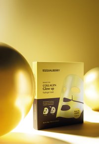 Pudełko maski hydrogelu w kolorze żółtym z czarnymi akcentami. Zawiera nazwę produktu oraz składniki; obejmuje ilustracje przed i po.