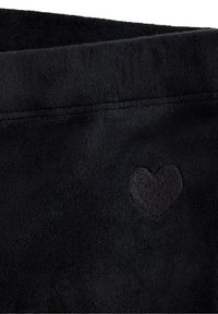 Tissu en polaire noir avec un subtil détail de cœur noir brodé. Texture lisse avec un bord plié et des coutures nettes.
