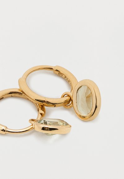 Arany karika fülbevalók ovális világoszöld drágakövekkel. Csiszolt felülettel és biztonságos kapoccsal rendelkeznek. A drágakövek texturált felületei visszatükrözik a fényt.