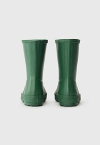 Galochas de borracha verde com um acabamento liso, design de tornozelo alto, solas texturizadas e detalhes em forma de onda na borda superior.