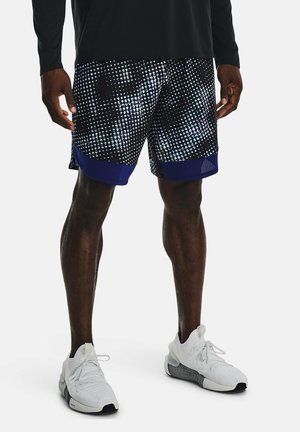 Mustat ja siniset urheilushortsit, joissa on pilkkukuvio, verkkohabitus ja rento istuvuus, yhdistetty valkoisten lenkkareiden kanssa.