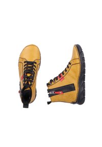 Bottes montantes en cuir jaune avec des accents noirs, dotées de lacets noirs, de garnitures rouges et d'un détail de fermeture éclair sur le côté. Semelle en caoutchouc flexible.