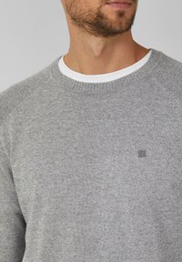 Grauer Strickpullover mit rundem Ausschnitt und gerippten Ärmeln. Verfügt über ein kleines Logo auf der Brust und eine weiße innere Kragenlage.
