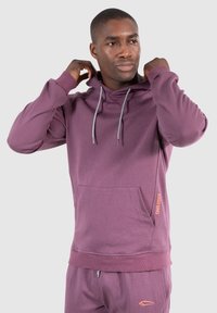 Felpa con cappuccio viola in tessuto morbido, con tasca davanti, lacci grigi e un logo arancione sul lato. Design slim-fit.