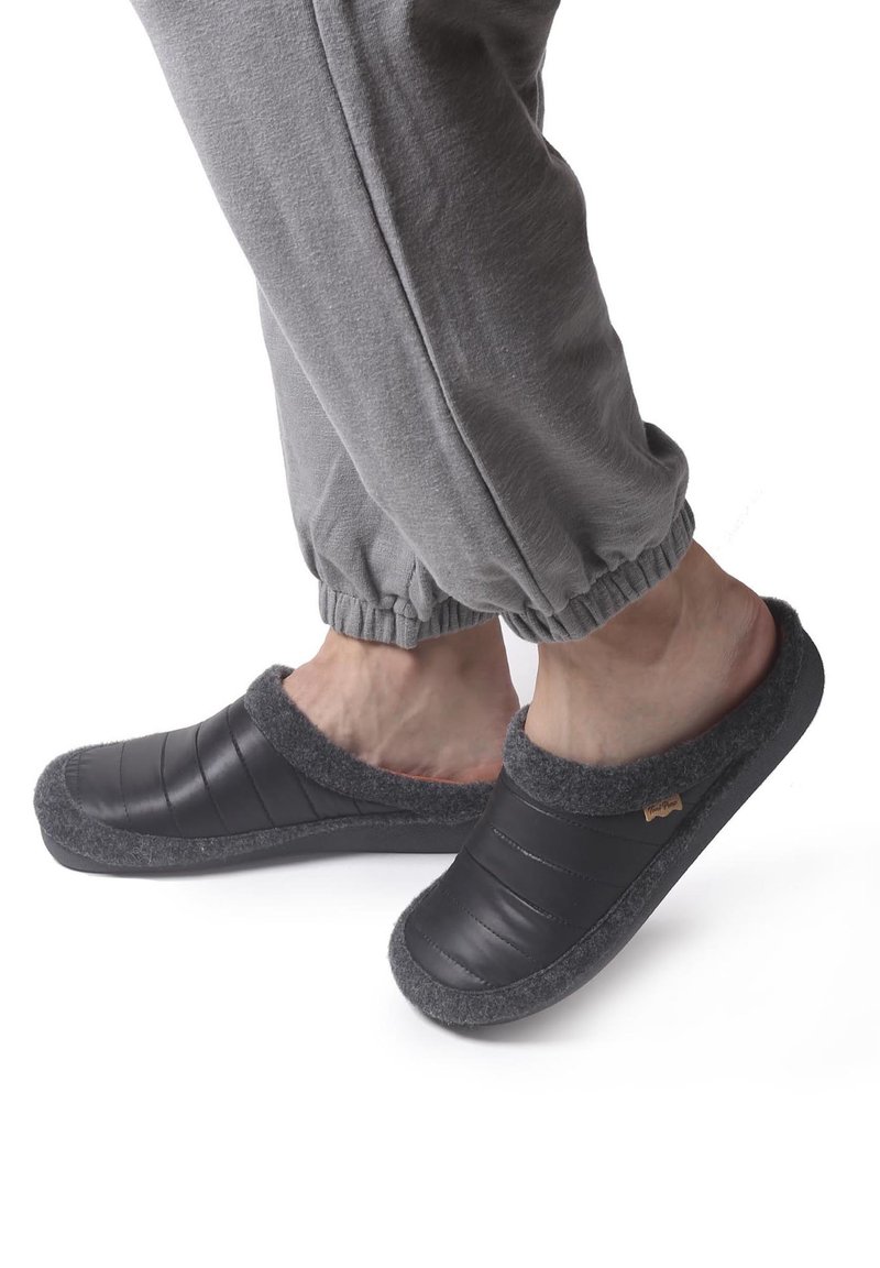 Crne papuče na slip-on sivi filc unutra, podstavljeni kviltani dizajn i teksturirana podloga za prianjanje. Nosi se uz sive trenirke.
