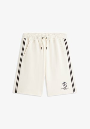 Shorts crème avec cordon de serrage, bandes latérales noires, poches sur les côtés et logo Tommy Hilfiger sur la jambe gauche.