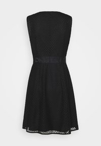Robe noire avec un motif en maille texturée, design sans manches et une ceinture large à logo DKNY bien visible. Silhouette trapèze avec une jupe évasée.