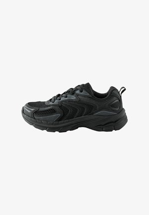 Czarny sportowy sneaker z siateczką i syntetycznymi nakładkami, teksturowaną podeszwą, sznurowaniem z przodu oraz pętelką z tyłu, przedstawiony z boku.