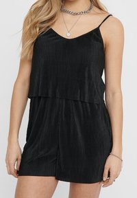 Mono negro acanalado con tirantes finos y un diseño en capas, con un corte relajado y una tela suavemente texturizada.