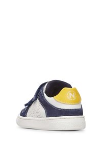 Sneaker navy e bianco con accenti gialli, realizzato in materiali lisci e testurizzati, con cinturino in velcro e pannelli laterali perforati.