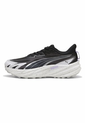 Chaussure de course Puma noire et blanche avec semelle épaisse mouchetée, fermeture à lacets à l'avant et logo sur le côté, montrée en profil gauche sur fond blanc.