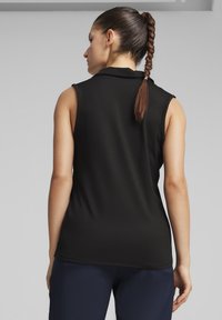 Top negro sin mangas con collar, textura suave y un diseño ajustado, mostrado desde la parte de atrás con un peinado de trenza.