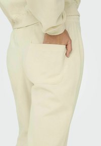 Beige Jogginghosen verfügen über eine Seiten- tasche, einen elastischen Bund und eine weiche, glatte Textur, die sich gut für die Freizeitkleidung eignet.