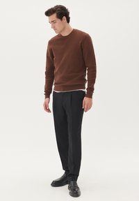 Brown knit sweater with round neckline, paired with black trousers and black loafers. Smooth texture and fitted silhouette.