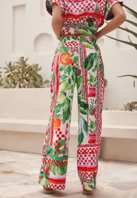 Široke hlače z vzorcem cvetličnih motivov v živahnih odtenkih zelene, rdeče in oranžne. Iz lahkega blaga z udobnim krojem in pasom z zategovalnim trakom.
