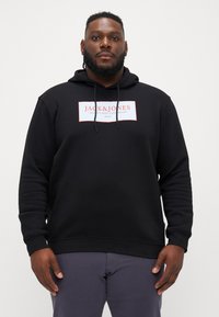 Black hooded sweatshirt made of soft fabric, featuring a white rectangular logo on the chest and adjustable drawstrings.