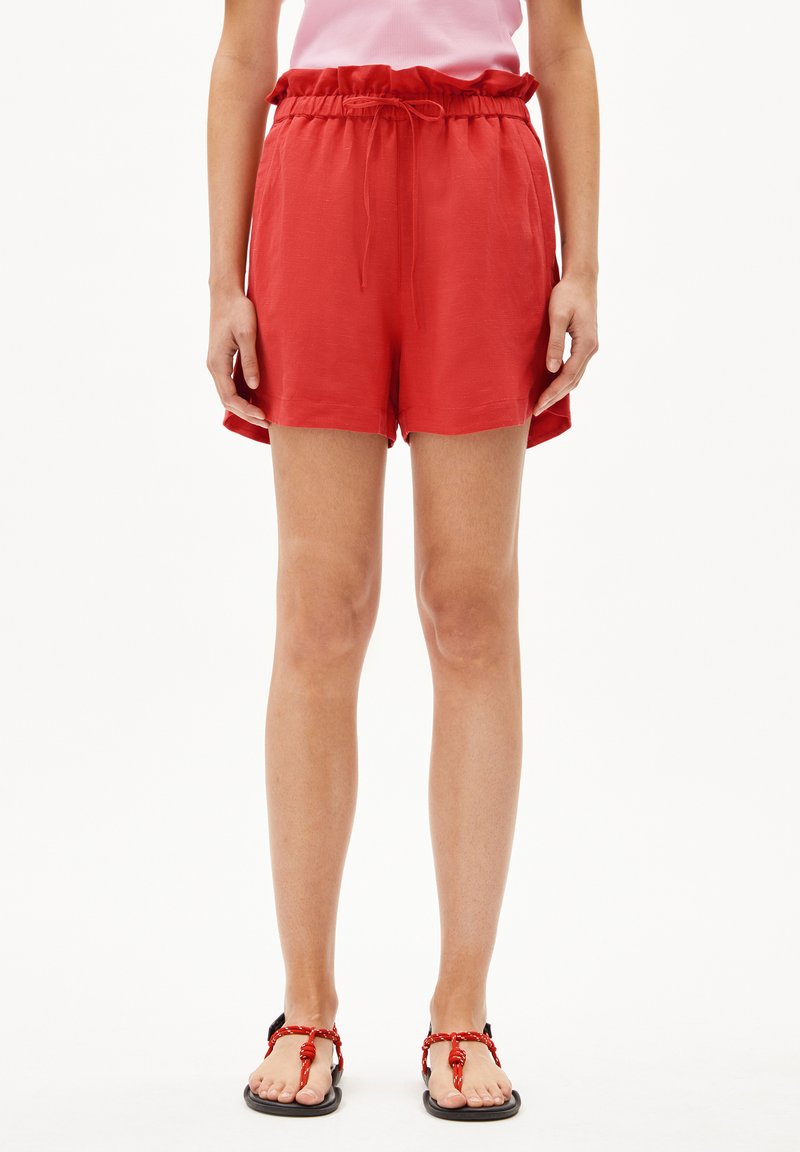 Shorts légers rouges avec une taille élastique et un cordon de serrage. Texture lisse avec une coupe décontractée et des poches latérales.