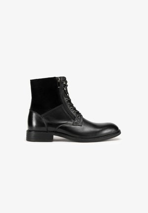 Czarne skórzane botki za kostkę o gładkim wykończeniu, z przodu sznurowane, z bocznym zamkiem błyskawicznym i teksturowanym panelem materiałowym nad piętą. Niski obcas w kształcie bloku.
