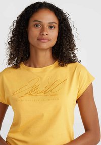T-shirt in cotone giallo con maniche corte, caratterizzato da testo in rilievo "O'Neill California" dello stesso colore. Design morbido e casual.