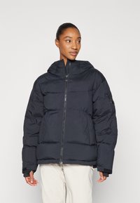 Black puffer jacket with a zippered front, hood, and ribbed cuffs. Features a rectangular quilted design and a side pocket. Textured fabric.