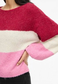 Maglione a maglia grossa con strisce rosse, bianche e rosa. Ha un colletto ampio e maniche a palloncino, con una finitura morbida e testurizzata.