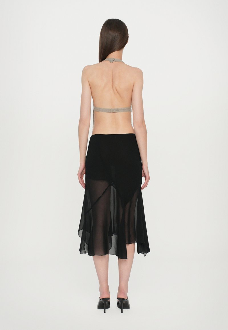 Black sheer maxi skirt with flowing design, paired with a light-colored halter top. Texture appears soft, lightweight fabric, and fitted silhouette.