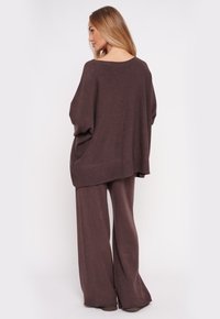 Brązowy dziany, oversize'owy sweter i szerokie spodnie w zestawie; miękka tekstura z luźnym krojem i obniżonymi ramionami; minimalistyczny design.