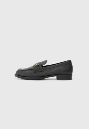Black leather loafers featuring a rounded toe, low block heel, and decorative gold hardware accent. Smooth texture with minimalist design.
