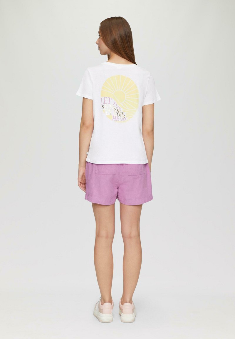 Wit T-shirt met korte mouwen, voorzien van een gele zonafbeelding en tekst op de achterkant. Gekocht met roze shorts en witte platform sneakers.