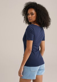 T-shirt a maniche corte blu navy realizzato in cotone morbido, design aderente, abbinato a pantaloni shorts in denim azzurro con tasche posteriori.
