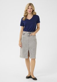 Mörkblå V-ringad t-shirt i kombination med en grå denimkjol med skräddarsydd passform som har en framslits och två sidofickor. Svarta baletttofflor fulländar outfiten.