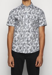 Lyhythihainen napillinen paita, jonka pohjaväri on vaaleansininen ja jossa on harmaa-musta lehtikuvio. Valmistettu sileästä, kevyestä kankaasta.