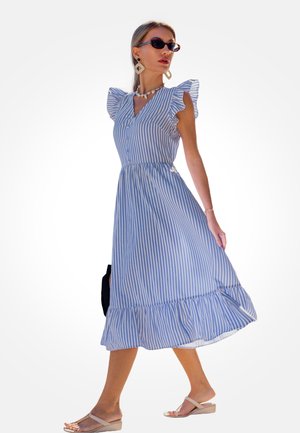 Sukienka w paski w kolorze niebieskim i białym, z krótkimi falbanianymi rękawami, dekoltem w kształcie litery V, zapinana na guziki z przodu oraz z falbanianym dołem. Noszona z sandałami.