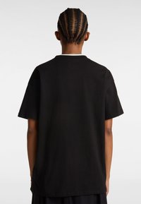 Camiseta de algodón negra con un corte relajado, mangas cortas y un escote redondo. La parte posterior presenta una marca mínima y costuras planas.