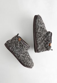 Graue gestrickte Hausschuhe mit einem strukturierten Muster, weichem Stoff und einem braunen Lederakzent. Wildlederähnliche Sohlen bieten Stabilität und Komfort.