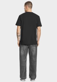Czarna bawełniana koszulka z krótkim rękawem, luźny krój i okrągły dekolt. Połączona z szarymi dżinsami z wyblakłą fakturą.