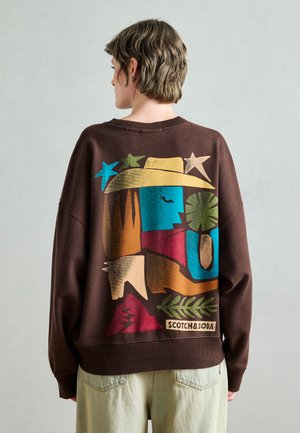 Brun genser med et fargerikt abstrakt design med former og mønstre. Rund hals, løs passform og logomerke ved kanten.