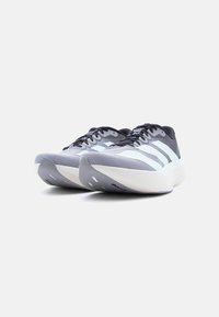 Ζευγάρι αθλητικά παπούτσια σε γκρι και λευκό με μαύρα κορδόνια, τοποθετημένα δίπλα δίπλα, σε λευκό φόντο.