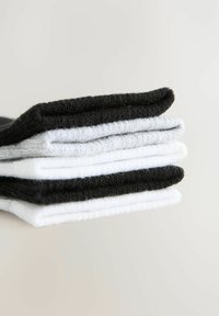 Chaussettes en coton empilées, de couleur noire, grise et blanche. Elles ont une texture lisse avec des bords simples et épurés.