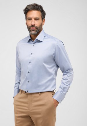 Hellblaues Hemd mit langen Ärmeln, klassischem Kragen, dunklen Knöpfen und glatter Textur; kombiniert mit beigen Hosen.