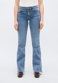 Világoskék farmerből készült, magas derekú, bőszárú farmernadrág öt gombos záródással, elülső zsebekkel és finom varrási részletekkel. Sima tapintású felület.