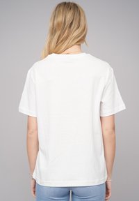 T-shirt en coton blanc à manches courtes et encolure ras du cou. Design simple, avec une texture lisse et une coupe standard.